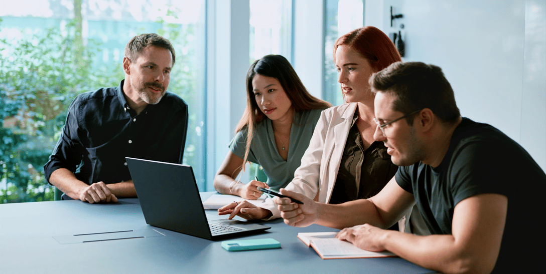 A group of IT experts gathered around a laptop discussing the results of an LLM benchmark run