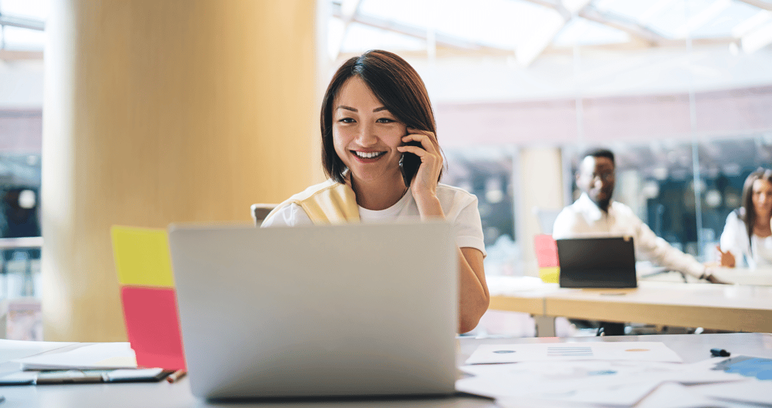 a woman talking on the phone looking at her laptop