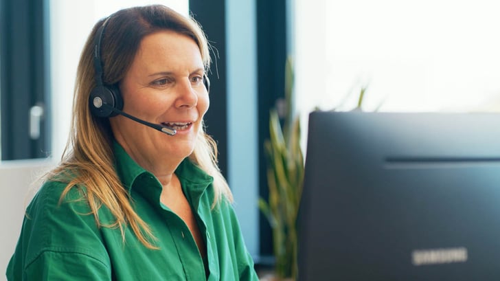 Mitarbeitende eines Service Center, die am Computer sitzt und über ein Headset telefoniert